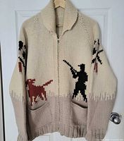 Front view of wool jacket on hanger showing hunter and dog motifs, pockets, zipper