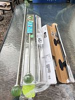 Overall lot showing silver adjustable rod with green glass finials, additional rods, and packaging