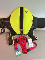 Arcadia Trail yellow flotation vest harness and red Great Choice harness laid out