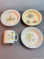 Overview of the four ceramic pieces: two plates, one bowl, one mug with alphabet rims and illustrations