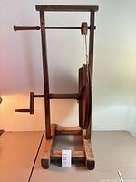 Full left-side view of wooden spool winder showing frame, wheel, crank handle, base
