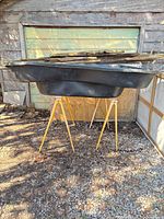 Black preformed pond liner upside down on sawhorses outdoors