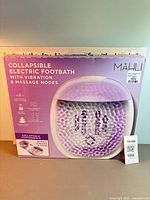 Retail box of Mahli collapsible electric footbath with canvas art partially visible behind