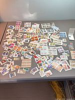 Wide view of entire spread of approximately 100–300 Canadian and international stamps on tabletop