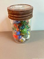 Full view of glass jar with rusty lid containing multicolored marbles