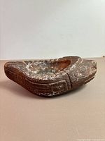 Side view of stone seal bowl showing carved head and flipper detail, white patina and abrasions