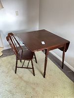 table with one leaf up, chair beside