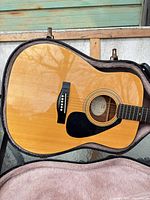 Full front view of Yamaha dreadnought guitar inside open pink-lined hard case