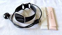 Fitbit Versa 4 with black band, USB charger, white and pink bands