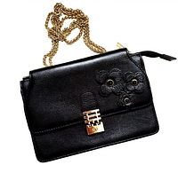 Front of black leather Florian London Mini Vienna bag showing flap, turn-lock clasp, flower appliqués, gold chain