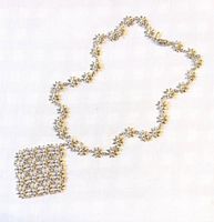 Full view of necklace laid flat showing daisy chain and square pendant