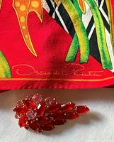 Corner of scarf showing print details and designer signature plus brooch
