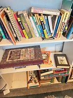 Shelves holding assorted paperback, hardcover and spiral-bound books on puzzles, gardening and reference subjects