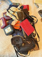 Pile of assorted small handbags, wallets and pouches on table surface