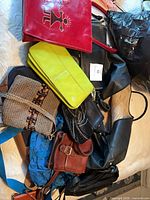 Pile of eight assorted handbags showing variety of colours and materials