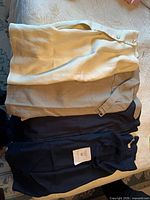 Three folded garments: cream skirt, beige skirt, navy skirt