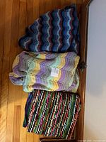 Stack of three crochet throws showing overall colors and patterns