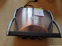 Closed grill showing stainless lid and brand logo