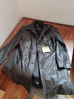 Front view of black leather trench coat laid flat showing overall style and condition