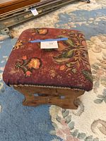 Top view showing red floral upholstered cushion and lot tag