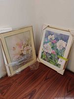 Both framed floral prints leaning against wall