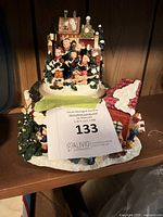 Front view of musical Victorian caroling village figurine showing carolers, houses, snow detail