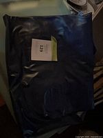 Folded navy vinyl air mattress with lot tag visible