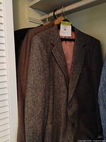 Gray herringbone tweed sport coat and part of additional brown blazer on shared hanger