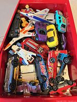 Top view of red box filled with mixed die-cast cars, trucks and airplanes