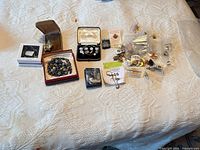 Entire lot laid out showing boxed items, bead jewellery and bagged pins