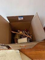 Open box showing assorted utensils and ceramic crock