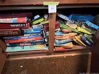 Cabinet shelf containing stacked vintage board game and puzzle boxes