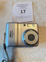 Front view showing lens, flash, Coolpix L4 branding and wrist strap