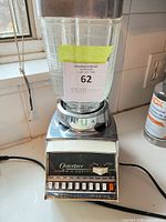 Front view of Osterizer blender showing chrome base, push-button panel, glass jar