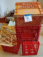 Stack of red and orange crates with beige crate leaning