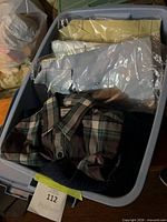 Bin containing packaged dress shirts and plaid shirt