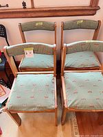 Front view of four matching chairs showing upholstery and wood frames