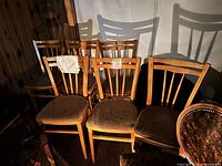 Six wooden dining chairs with fabric seats grouped together