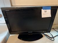 Front view of Sharp Aquos LCD television on stand with screen off