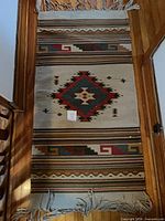 Full view of rug showing central diamond motif, striped borders and fringe
