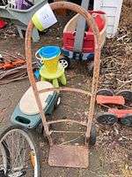 Front view of rusted steel hand truck showing handle, footplate and wheels