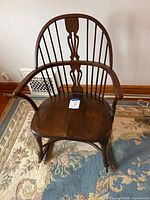 Front view of mahogany Windsor rocking chair showing spindle back, armrests and contoured seat