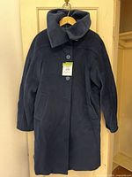 Full view of navy women’s coat on hanger showing collar, pockets and length