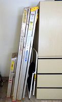 Four folded ladders and step stool leaning against cabinet