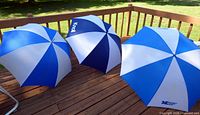 Three open blue and white golf umbrellas on deck