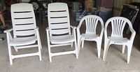 Four white plastic patio chairs: two high-back recliners and two stackable armchairs