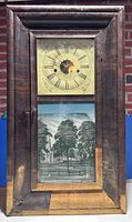 Front view of clock showing dial, reverse painted lower glass, veneer loss