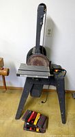 Full view of belt/disc sander on stand with extra belts on floor