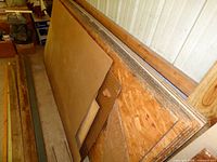 Stack of OSB sheets, Masonite sheet, pegboard, and adjacent lumber pieces