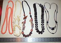 Top-down view of five chunky necklaces with ruler for scale